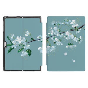 May include: A blue tablet case with a floral design featuring white cherry blossoms and green leaves. The case has a flap that folds over the tablet.