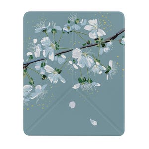 以下が含まれることがあります： くすんだ青色の背景に、暗い枝に咲く白い桜の花が描かれた長方形の電子書籍リーダー用保護カバー。デザインには、散らばった黄色い点と2枚の落ちる花びら、そして折り目が含まれています。
