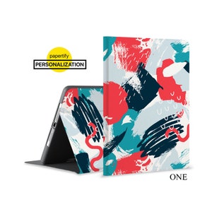 May include: A tablet case with a colorful abstract design featuring red, blue, and black brushstrokes on a white background. The case is folded to show the inside of the case, which is black. The text "ONE" is printed on the bottom right corner of the case.