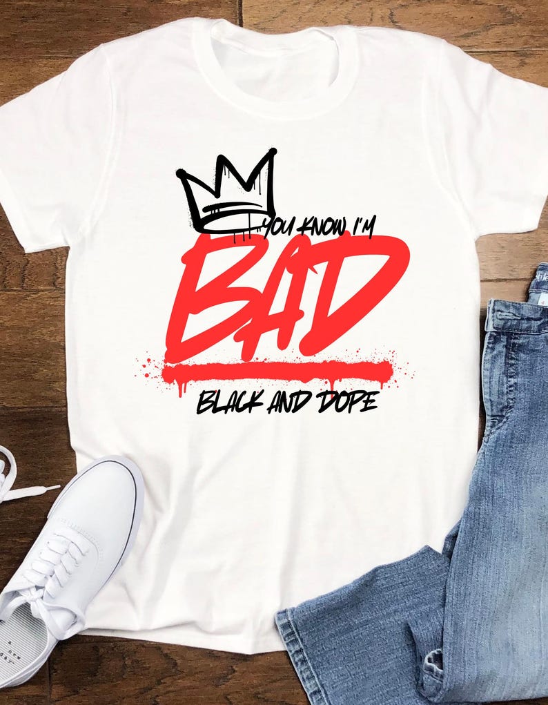 May include: White t-shirt with a black crown graphic above the red text "BAD". The phrase "YOU KNOW I'M" is above the word "BAD", and "BLACK AND DOPE" is below it. A pair of white sneakers and blue jeans are visible.