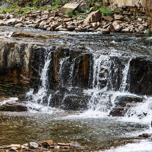 May include: A cascading waterfall flows over a series of rocky steps, creating a picturesque scene in nature.