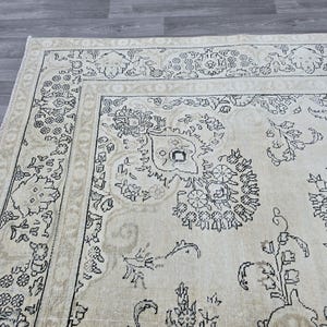 May include: A rectangular area rug featuring a cream-colored base with intricate black line-drawn floral and botanical patterns. The design includes a wide decorative border with repeating motifs and a central field filled with scattered floral elements.