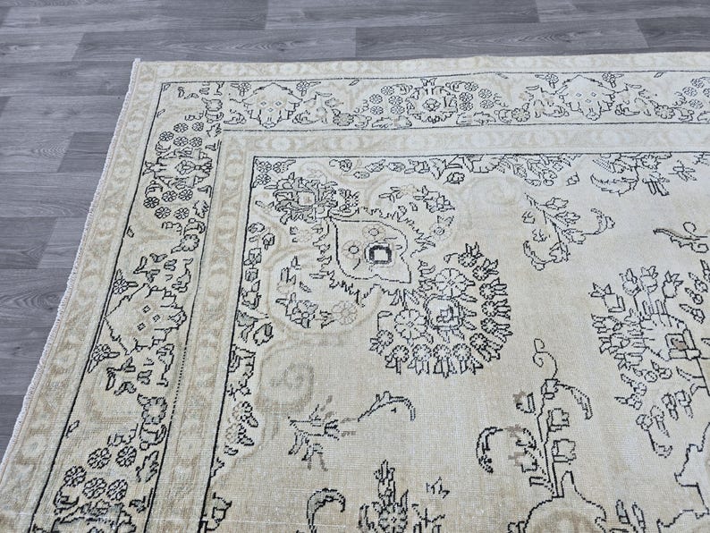 May include: A rectangular area rug featuring a cream-colored base with intricate black line-drawn floral and botanical patterns. The design includes a wide decorative border with repeating motifs and a central field filled with scattered floral elements.