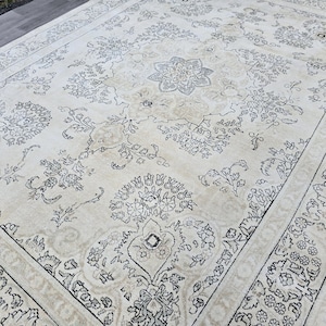 May include: A large rectangular area rug featuring a cream-colored background with intricate black line-drawn floral and geometric patterns. The design includes a central medallion surrounded by symmetrical botanical motifs and a wide decorative border.