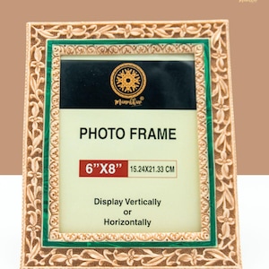 May include: A decorative photo frame with a gold and green finish. The frame has a floral design and the text "PHOTO FRAME 6"x8" 15.24x21.33 CM Display Vertically or Horizontally".