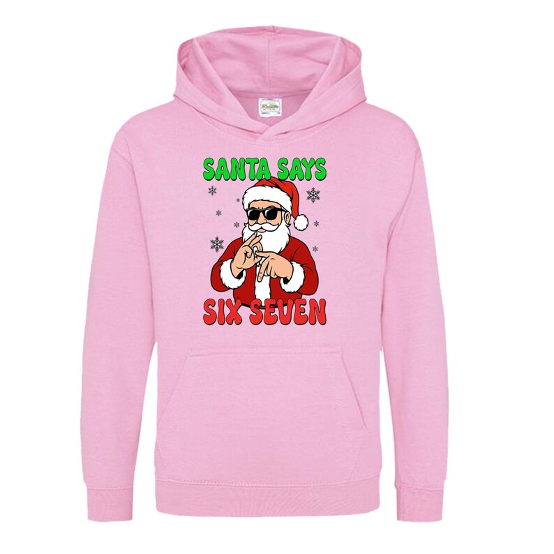 May include: A light pink hooded sweatshirt featuring a graphic of Santa Claus wearing sunglasses and making a hand gesture. The text "SANTA SAYS" is above the Santa graphic, and "SIX SEVEN" is below.