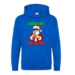 May include: A blue hooded sweatshirt featuring a graphic of Santa Claus wearing sunglasses and making a hand gesture. The text "SANTA SAYS" is above the Santa graphic, and "SIX SEVEN" is below.