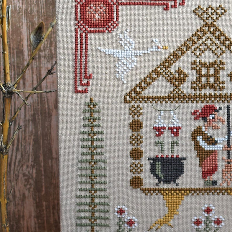 May include: Cross-stitch sampler featuring a whimsical scene with a house, goose, and witch. The design uses brown, red, green, and white thread on a beige background. A tree and flowers are also included in the design.
