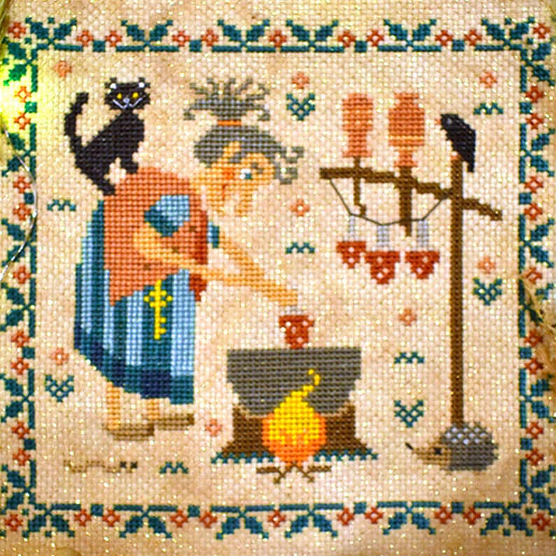 May include: A cross-stitch embroidery depicting a witch stirring a cauldron over a fire. The witch is wearing a red and blue dress and has a black cat on her shoulder. There are three birds perched on a wooden post in the background.