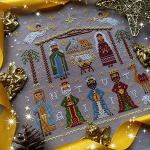 K&ouml;nnte beinhalten: Eine detaillierte Kreuzsticharbeit, die die Weihnachtsgeschichte darstellt. Das Design zeigt die Heilige Familie, die Heiligen Drei K&ouml;nige, Engel, Sterne und Palmen, alles in verschiedenen Farben auf einem neutralen Hintergrund. Das Wort "M A G I" ist gestickt.