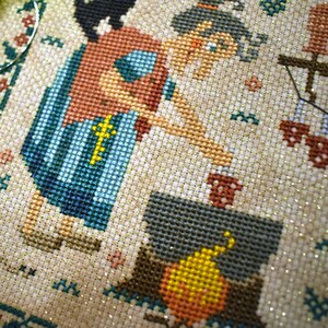 May include: A cross-stitch pattern of a woman in a blue and red dress holding a cup, standing next to a fireplace with a yellow and orange fire.