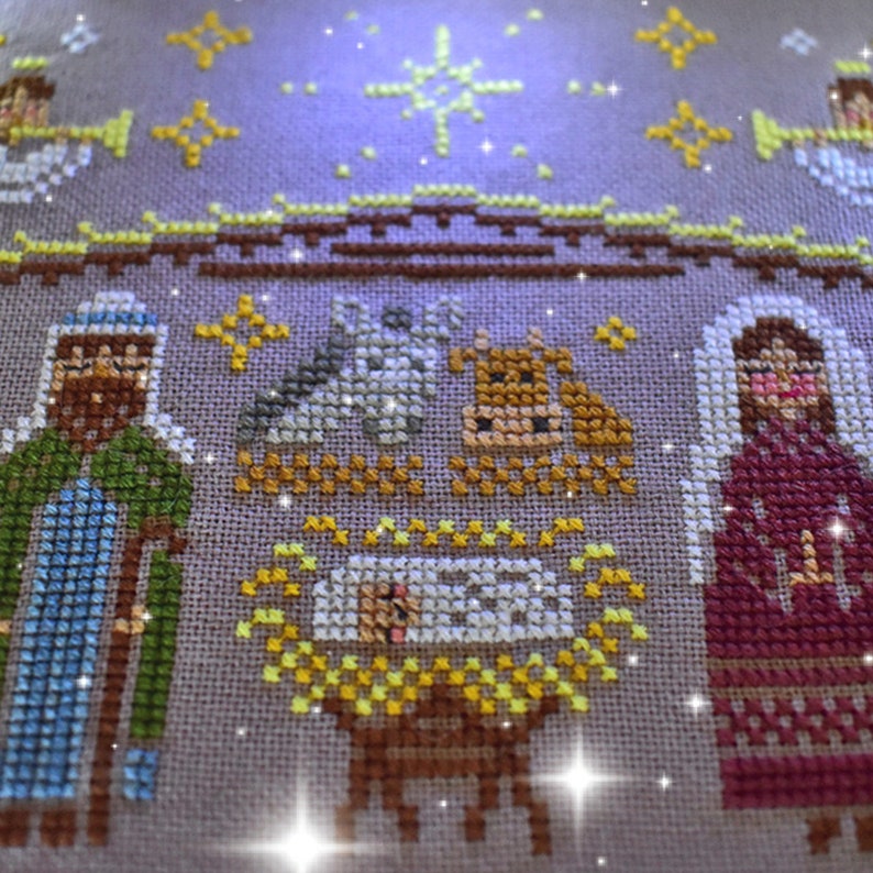 K&ouml;nnte beinhalten: Kreuzstich-Stickerei, die eine Weihnachtskrippe darstellt. Das Kunstwerk zeigt die Figuren von Josef, Maria und dem Jesuskind in einer Krippe, zusammen mit einem Ochsen, einem Esel und Engeln. Die Farbpalette umfasst Braunt&ouml;ne, Gr&uuml;n, Gelb und Rot.