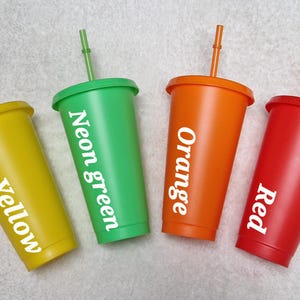 May include: Four reusable tumblers with lids and straws. The tumblers are yellow, neon green, orange, and red. Each tumbler has a white label with the colour name printed on it.