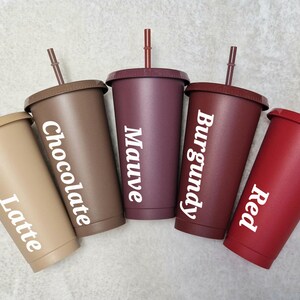 May include: Five reusable plastic tumblers with lids and straws in different colours: latte, chocolate, mauve, burgundy, and red. Each tumbler has a colour name printed on it.