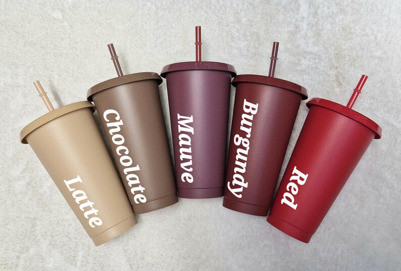 May include: Five reusable plastic tumblers with lids and straws in different colours: latte, chocolate, mauve, burgundy, and red. Each tumbler has a colour name printed on it.