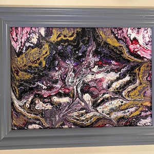 May include: Abstract painting in a gray frame. The painting features swirling patterns of gold, purple, black, and white paint.