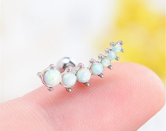 May include: A silver curved bar with a small ball at the end and seven white opal stones.