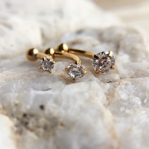 Puede incluir: Tres aros de oro con piedras de circonita c&uacute;bica transparentes. Los pendientes son de diferentes tama&ntilde;os, con la piedra m&aacute;s grande en el centro.
