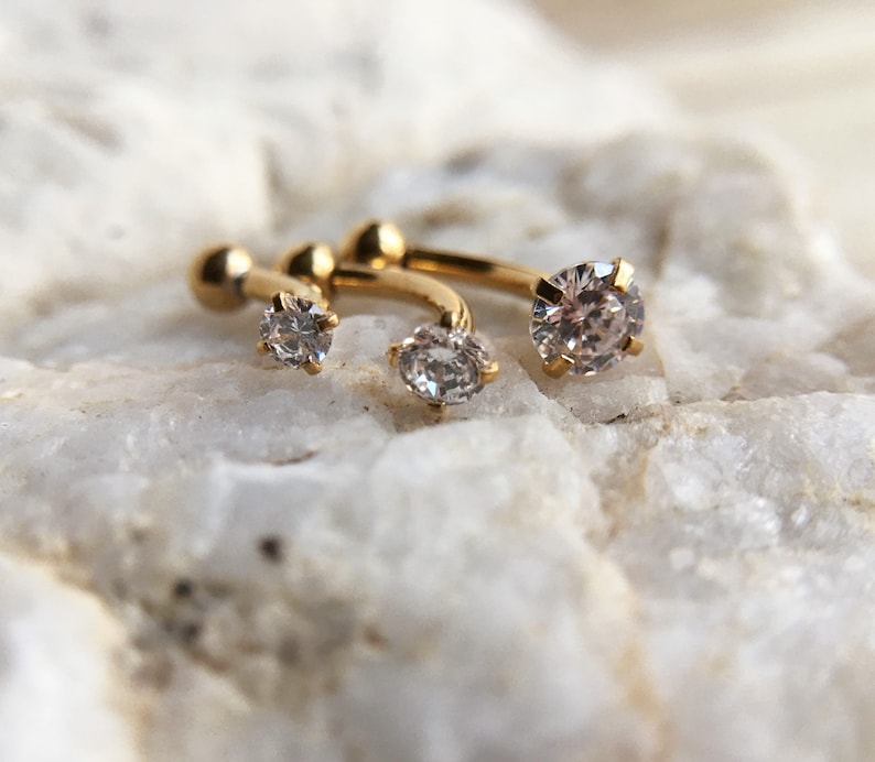 Puede incluir: Tres aros de oro con piedras de circonita c&uacute;bica transparentes. Los pendientes son de diferentes tama&ntilde;os, con la piedra m&aacute;s grande en el centro.