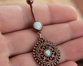 May include: A rose gold belly button ring with a dangling charm. The charm is a circular design with an opal stone in the center. The ring has a small opal stone on the top.