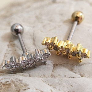 May include: Two barbell style body jewelry pieces with a clear crystal flower design. One is gold and the other is silver.