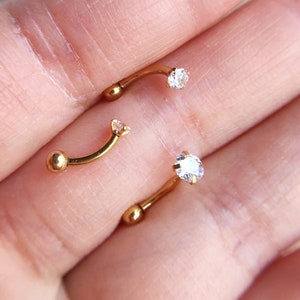 Puede incluir: Tres piezas de joyer&iacute;a corporal de barra curva de color dorado con acentos de cristal transparente.