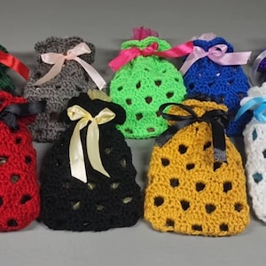 May include: Ten crocheted drawstring bags in various colors, including red, green, black, white, blue, and yellow. Each bag has a different colored ribbon tied around the top.