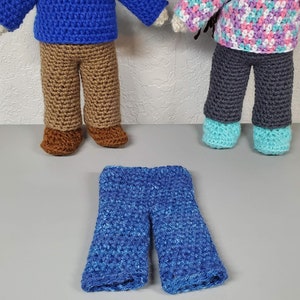 May include: Three pairs of crocheted pants for dolls. One pair is brown, one is gray, and one is blue.