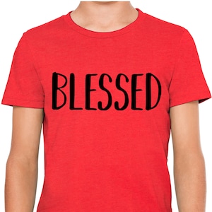 以下が含まれることがあります： 黒文字で「BLESSED」とプリントされた赤いTシャツ