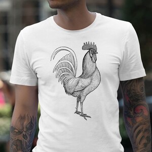 May include: A white t-shirt with a black and white illustration of a rooster.