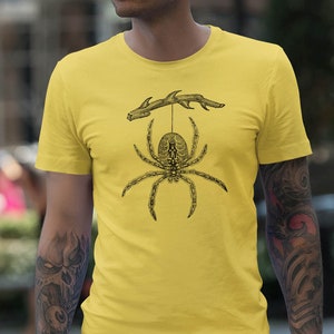 May include: A yellow t-shirt with a black and white illustration of a spider hanging from a branch.