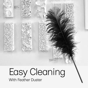 May include: A black feather duster with a long handle is displayed in front of white wall art. The wall art consists of various white, textured, rectangular pieces. The text "Easy Cleaning With Feather Duster" is at the bottom.
