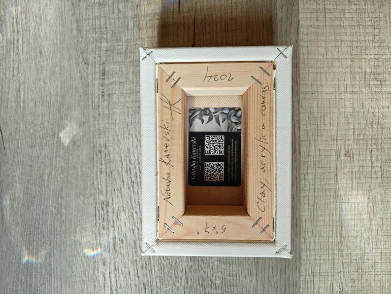 May include: Back of a stretched canvas art piece. The wooden frame is stapled to the canvas. The artist's name, "Natasha Kanevski", is written on the frame. A business card is visible in the center. The canvas measures 5x7 inches.