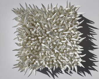 Puede incluir: Escultura de cerámica blanca con una superficie texturizada y puntiaguda. La escultura tiene forma cuadrada y una apariencia tridimensional.