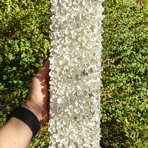 May include: White ceramic wall sculpture with a textured surface. The sculpture is made up of many small, irregular shapes that resemble flowers.