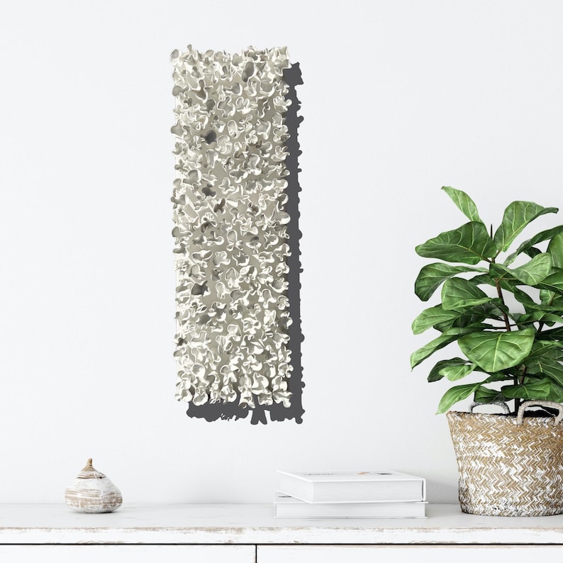 May include: White ceramic wall sculpture with a textured, organic shape. The sculpture is mounted on a white wall and casts a shadow.