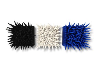 Könnte beinhalten: Drei quadratische Wandkunstwerke in Schwarz, Weiß und Blau. Jedes Stück hat eine strukturierte Oberfläche mit zahlreichen spitzen Vorsprüngen. Die Kunstwerke sind horizontal vor einem weißen Hintergrund angeordnet.