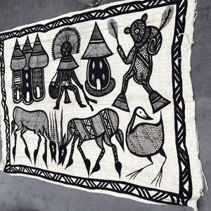 May include: Black and white textile art featuring stylized figures, animals, and structures. The artwork includes depictions of animals, human-like figures, and geometric patterns. The border has a repeating triangular design.