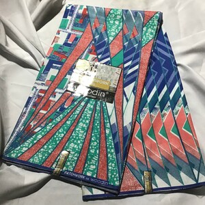 Puede incluir: Dos piezas de tela con un patrón geométrico en tonos de azul, verde y rosa. La tela está etiquetada "Patchwork de Woodin" y "Woodin"