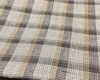 Puede incluir: Primer plano de una tela con un patrón de cuadros marrones y beige. La tela tiene una textura tejida y está hecha de un material suave y cómodo.
