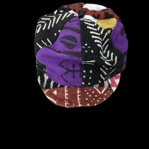 May include: A patchwork cap with a variety of patterns and colors. The cap features sections of black, white, purple, and brown fabric. The patterns include geometric shapes and abstract designs.