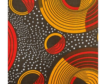 Tela estampada africana, fondo negro con motas blancas, círculos espirales rojos y dorados, récords **[mínimo 2 yardas]**
