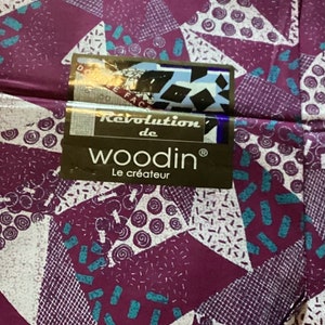 May include: A close-up of a purple and white fabric with a geometric pattern. The fabric has a label that says "Revolution de woodin Le créateur".