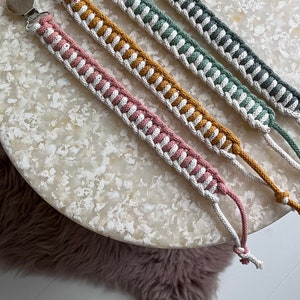 May include: Four crocheted dummy clips with silver clips. The clips are in shades of pink, yellow, green, and grey.
