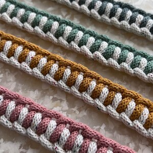 May include: Four different colours of braided rope trim with white speckles. The colours are grey, green, mustard yellow, and pink.