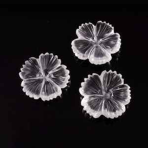May include: Three clear, colorless, transparent carved gemstone flowers. Each piece features a five-petaled floral design with radial grooves extending from the center to the scalloped edges, creating a faceted, reflective appearance.