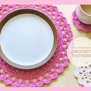 May include: Pink crochet doily with a brown plate on top. The doily is on a wooden surface. There are two smaller white crochet doilies and a white mug with brown liquid on the surface. The text "THE ALPACA STUDIO CROCHET PATTERN" is on a white circle.