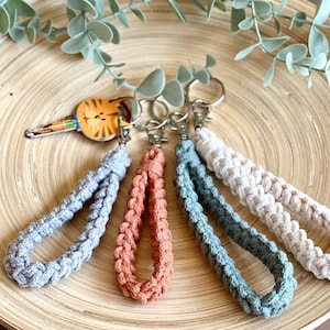 May include: Four crocheted keychains in gray, orange, teal, and cream colors. The keychains are attached to silver key rings.