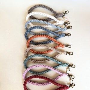 May include: A set of ten crocheted keychains in various colors, including brown, white, gray, orange, beige, green, and pink. Each keychain has a metal clasp.