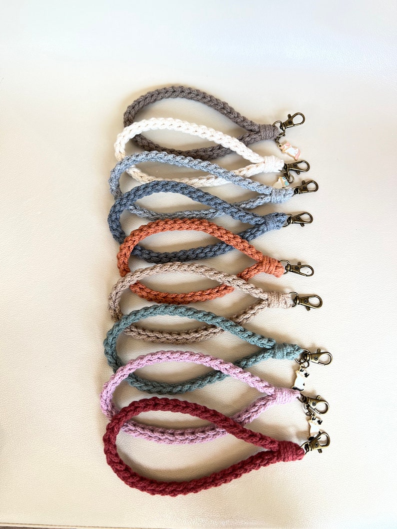 May include: A set of ten crocheted keychains in various colors, including brown, white, gray, orange, beige, green, and pink. Each keychain has a metal clasp.